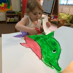 Sophie cuts out her lovely dolphin painting.