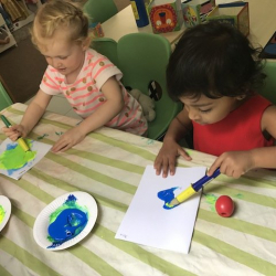 Elodie and Mira working on their blue and yellow colour mixing craft.