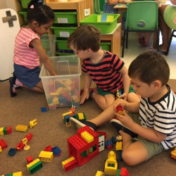Avyanna, Charlie, and Thomas build with Duplo blocks.