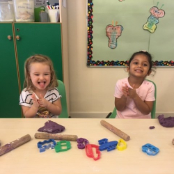 Happy girls Matilda and Avyanna play with the purple play do