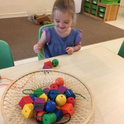 Matilda enjoying threading beads.