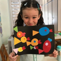 Emily makes a fish picture with cut out shapes.