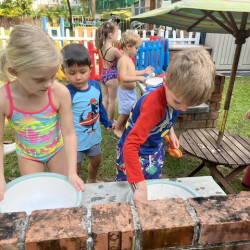 Busy bees using loved using mud kitchen during splash time .