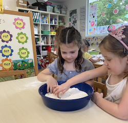 The girls showing each other the CVC words they are tracing.