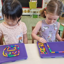 Xiao Yan and Olive patiently arranging the beads on their tray.