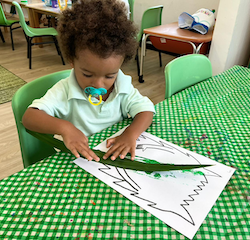 Teddy decorating his green monster by using paint and leaves!