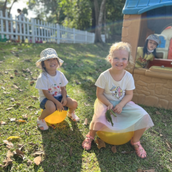 Eve & Louise pretending to be mother hens sitting on their eggs .