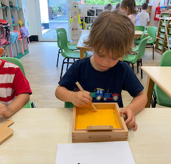 Hugo practicing writing letter J on the sand tray!