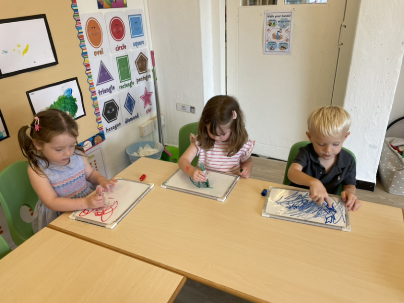 Lily, Clemmie and George drawing on the white boards.