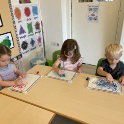 Lily, Clemmie and George drawing on the white boards.