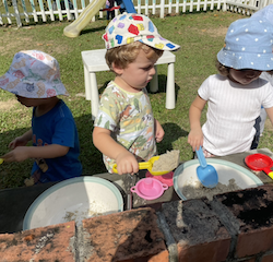 Dylan and Margot making pancakes in the mud kitchen.