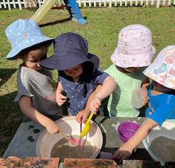 Margot, Thomas, Avery and Norielle are making a special creation in the mud kitchen.