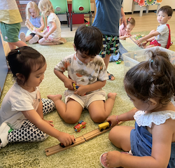 Allie, Anaya and Kathavya working together to build the train tracks.