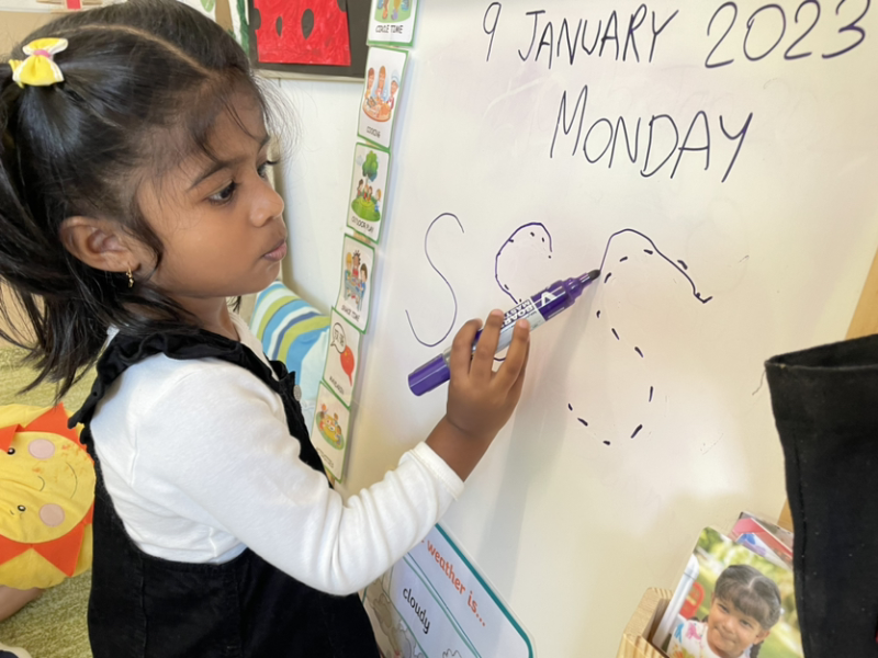 Kaavya practising writing letter “S” on the white board!
