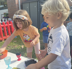 Clemmie and Rowan preparing mud pie during mud kitchen time!