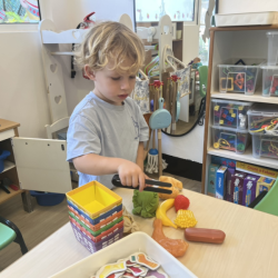 Kingston practicing his fine motor skills by grabbing fruits with a tong. 