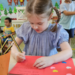 Esme focusing on her writing for her Christmas greeting card.