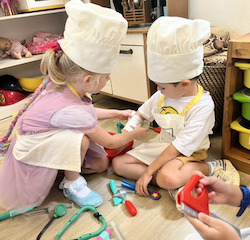 Regan and Finley having fun with doctor set pretend play .
