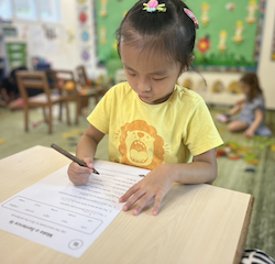 Lucy independently completing her reading and writing activity.