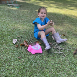 Vivi using twigs and leaves to make pretend marshmallows on sticks.
