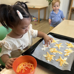 Harper sprinkling some cheese on her fish puff pastry!