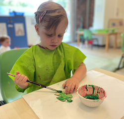 Izzy is painting a Christmas tree ornament.