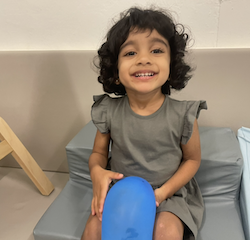 Nila is having fun with a balloon in the soft play room.