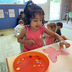 Nila is putting buttons on her butterfly.