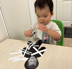 Cara pasting strips of paper on her mummy craft!