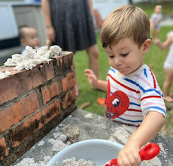 Jasper working really hard on making a row of sand shapes on the brick wall.