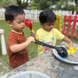 Wesley in mud kitchen play with a friend from the butterflies class