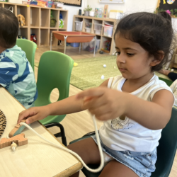 Kai threading large wooden beads!