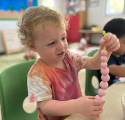 Arthur threading beads with pipe cleaners.